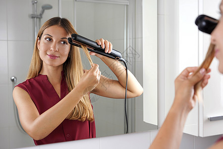 女孩用蒸汽清洁器 在浴室镜子上梳理头发图片
