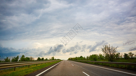 暴风雨前日落时的高速公路交通旅行车辆橙子驾驶农村路线街道太阳蓝色运动图片