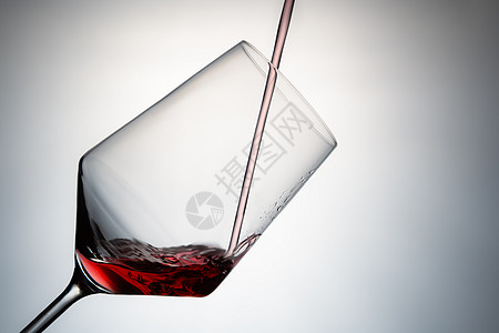 用红酒装满水晶杯的特写镜头 将红酒倒入隔离在灰色背景上的水晶玻璃杯中 要剪切的图像 概念饮料图片