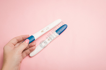 粉红色背景下的妊娠试验在手 阳性试验 怀孕复制空间孩子家庭婴儿母性女孩症状药物条纹摄影生育力图片
