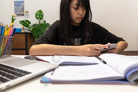 亚裔女学生在书桌上写家庭作业和阅读书大学教育班级绘画房间学生知识分子笔记本瞳孔教科书图片