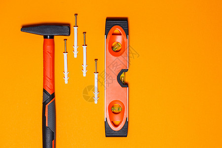 维修工具 钉子锤 水平仪 橙色背景墙上的销钉 向导工具包钻头测量书签房子统治者钥匙锤子塑料六边形建设者图片
