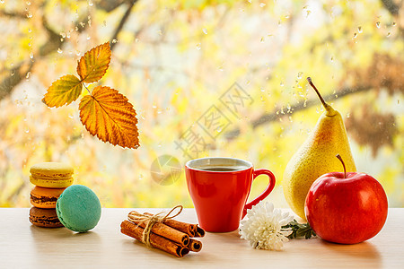 马卡罗翁 一杯咖啡加肉桂棒 和窗玻璃上秋黄色的叶子 在模糊背景下滴水图片
