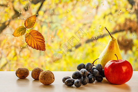 窗玻璃上的胡桃 梨 葡萄 苹果和秋黄色叶 其底底部模糊 有水滴图片