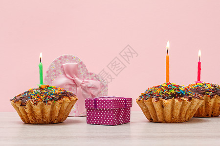 生日松饼和烧着的节日蜡烛 还有粉红色背景的礼物盒盒子甜点生日小吃磨砂火焰派对食物念日燃烧图片