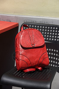 在黑椅子上背背包的红皮手提包女性皮革书包配饰口袋行李魅力奢华拉链图片