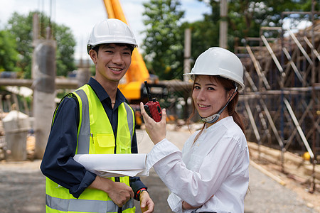 结构工程师和建筑师讨论并使用户外建筑工地的蓝图进行工程研究与工作以及团队合作项目男人会议工厂头盔检查建筑学检查员图片