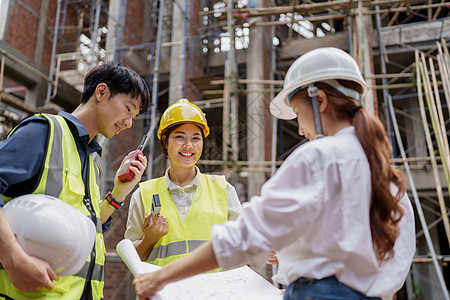 结构工程师和建筑师讨论并使用户外建筑工地的蓝图进行工程研究与工作以及职场安全职业团队安全帽检查建筑学控制人士交易图片