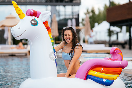 女人在泳池里用可充气的独角兽玩具床垫漂浮海滩火烈鸟旅游泳装旅行比基尼粉色日光浴假期女士图片
