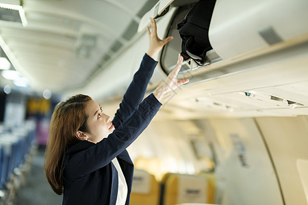 女商务人士把行李放在飞机的顶端架子上图片