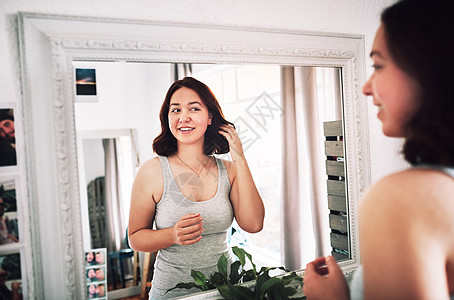 我为我现在的样子而活 一个迷人的年轻女人在家里的卧室里站在镜子前欣赏自己图片