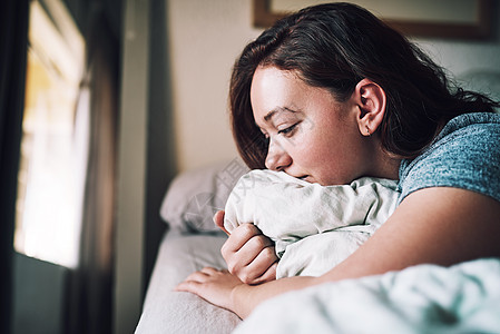 她醒来时心碎了 一个迷人的年轻女人 在家里躺在床上的时候 看着忧郁不悦的样子图片