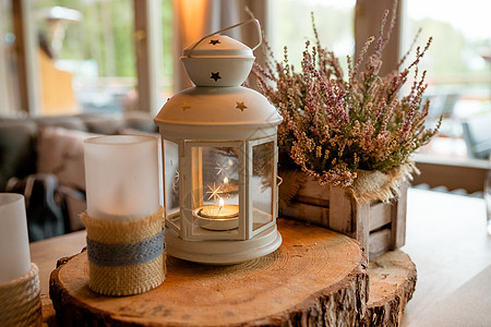 白色灯笼 里面燃烧着蜡烛 站在装饰着木片和背景花的节日餐桌上 装饰风格 婚礼 秋季静物 色调图像 粉红色石南花图片