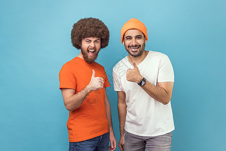 两个男人举起拇指 装模作样地拍照和微笑 表示赞同图片