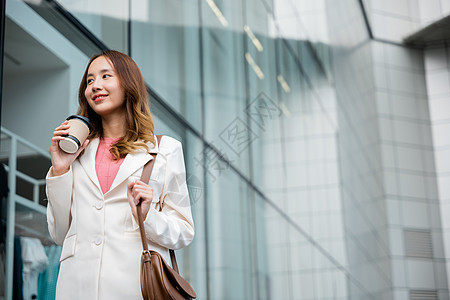 拥有咖啡杯的女商务人士 去上班 她走在办公室大楼附近行走工人套装快乐人士管理人员女性街道微笑杯子城市图片