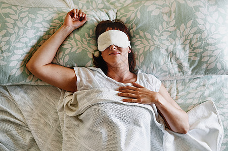 我今天不想起床 一个迷人的年轻女人在家里的床上戴着睡眠面罩睡觉图片