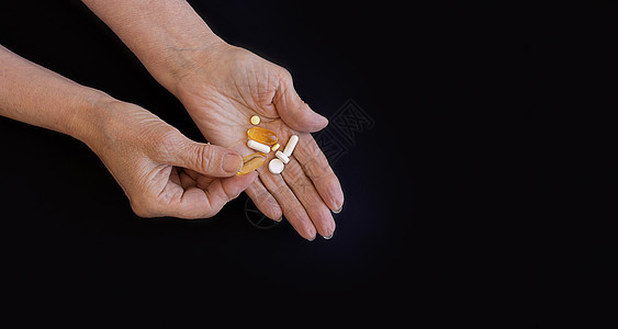 年长妇女选择吃什么药丸 拿黑底的手矿物质疾病养护压力痛苦安乐死治疗成人药店维生素图片