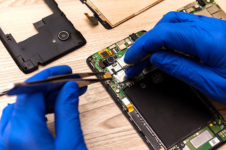 修理智能手机主机板的技师 在桌子上的工作间里细胞芯片母板损害电路工程技术员实验室焊接维修图片