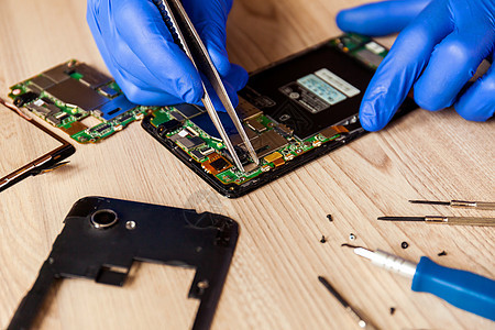 修理智能手机主机板的技师 在桌子上的工作间里男人商业实验室工程师技术员电气硬件损害工程服务图片