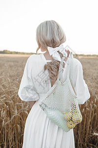 穿着长长白裙子的金发女子在小麦田中行走 即结婚和自然走路的概念享受农业田园风光礼服草地头发收成女士日出图片