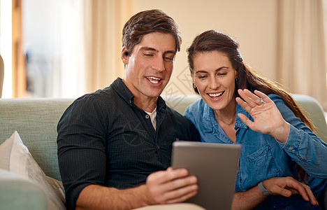 向国外的家人问好 一对夫妇使用数字平板电脑 同时在家休息图片