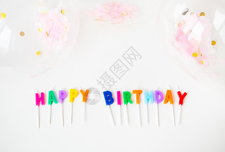 写着 生日快乐 的多彩蜡烛 连同彩色纸条 假日和惊喜概念一起 在白色背景上隔绝图片