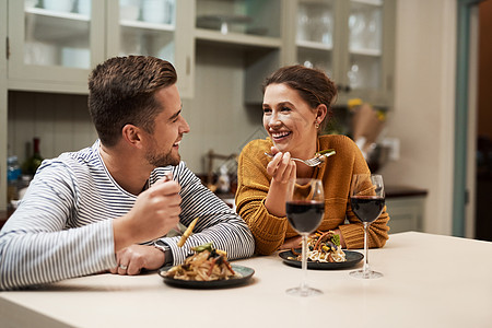 谁不喜欢家常菜 一对恩爱的年轻夫妇在家里的厨房里享用晚餐时相视而笑图片