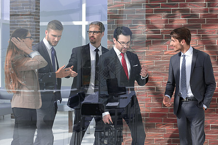 站在玻璃墙后面的现代办公室里的人企业家团体讨论团队职业领导伙伴职场商务会议图片