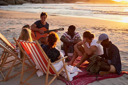 我写了一首关于我们友谊的歌 一个男人和他的朋友坐在沙滩上弹吉他图片