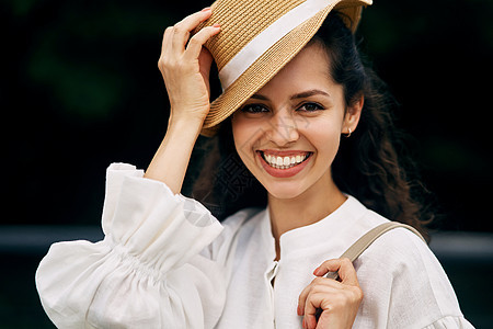 一个微笑的女孩的肖像 和戴着帽子的卷卷头发黑发女孩图片