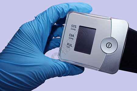 医生用蓝色医疗手套的手握着一个计时器 医学概念测试监视器诊断压力展示疾病仪表电子产品手腕药品图片