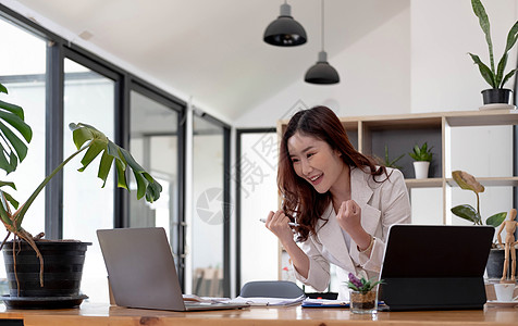 在工作场所办公室用笔记本电脑成功取得胜利的亚洲商业妇女 快乐兴奋成功的亚洲女商务人士图片
