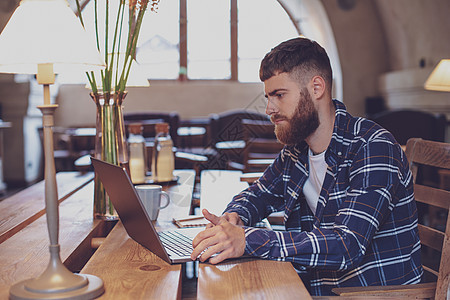 年轻专业专业人员在咖啡馆的笔记本电脑上上网男人享受桌子职业互联网学生咖啡衬衫饮料自由职业者图片