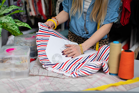 缝纫工用纸裁缝的模具做成条纹织物图片