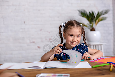 鼓动坐在桌边的小女孩 用蜡笔画画画或者在家工作绘画沉思学校铅笔童年桌子创造力快乐幼儿园艺术家图片