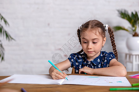 鼓动坐在桌边的小女孩 用蜡笔画画画或者在家工作享受笔记本沉思铅笔画家艺术家学校女孩蜡笔创造力图片
