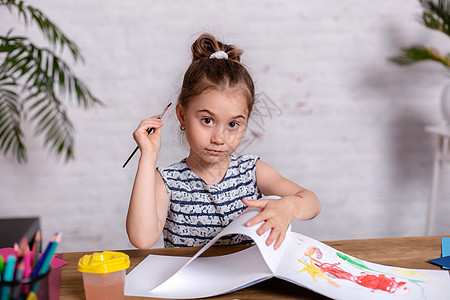 鼓动坐在桌上的小女孩 用油漆画画画笔记本创造力教育专辑工作室学校铅笔画家女孩快乐图片