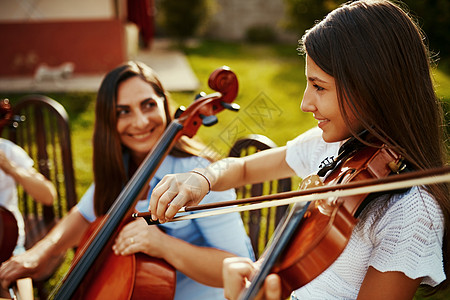 我从妈妈那里学到了对音乐的热爱 一位美丽的母亲在户外和她可爱的女儿一起演奏乐器图片