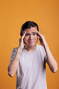 亚裔男子头痛情感疾病学生男人工作室手势橙子疼痛鬼脸青少年图片