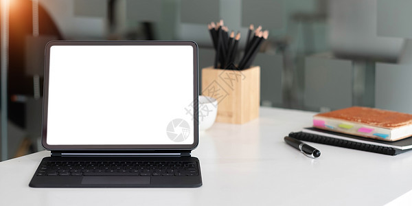 在办公室的木制桌子上 装有魔法键盘的空白屏幕板电脑空间桌面杯子药片展示咖啡房间商业监视器图片