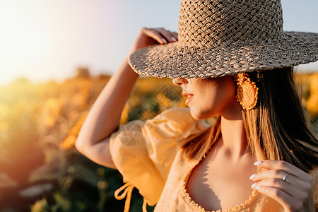 穿着草帽的神秘陌生女人 假扮在向日葵的背景上 开阔的田野 古老的复古风格服装图片