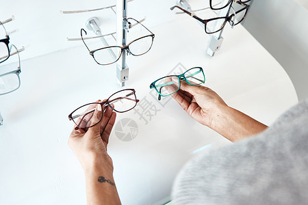 在零售眼镜店和里面的验光师购买 寻找和购买眼镜 持有商店存货的顾客试图决定一种新的现代风格 时尚和时尚的镜框 以便在销售时购买图片