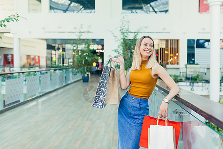 快乐的年轻购物妇女拿着纸袋买东西 微笑着笑容喜悦购物者享受购物中心女孩购物狂女性零售相机黑色图片