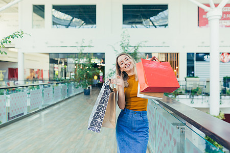 快乐的年轻购物妇女拿着纸袋买东西 微笑着笑容购物者客户女性购物狂顾客女士黑色店铺购物中心女孩图片