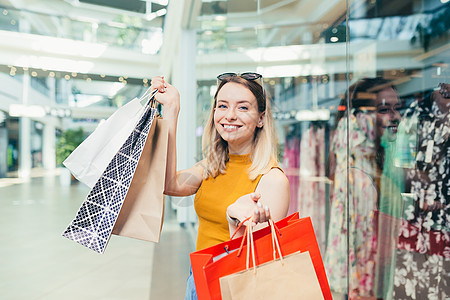 快乐的年轻购物妇女拿着纸袋买东西 微笑着笑容喜悦零售购物中心销售客户相机享受顾客购物狂黑色图片