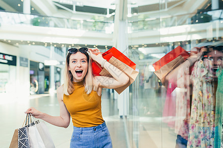快乐的年轻购物妇女拿着纸袋 带着购买和微笑着笑容图片