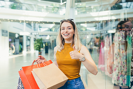 快乐的年轻购物妇女拿着纸袋买东西 微笑着笑容购物狂女性女孩喜悦黑色享受购物中心购物者女士销售图片