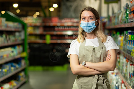 女售货员的肖像 在保护性面罩中 妇女微笑和看着相机部门大卖场围裙快乐店铺营业员面具杂货商走道女士图片