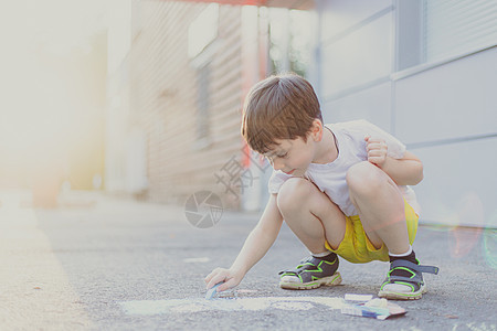 男孩在沥青上画着有蜡笔的生活方式 儿童班 儿童绘画 儿童心理学游戏创造力孩子们太阳童年艺术学校幼儿园人行道路面图片