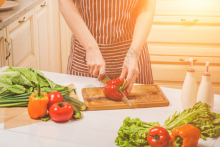 在家里厨房做饭的年轻女子 一个女人用刀割胡椒和蔬菜 笑声沙拉饮食食谱女孩主妇桌子营养早餐晴天烹饪图片